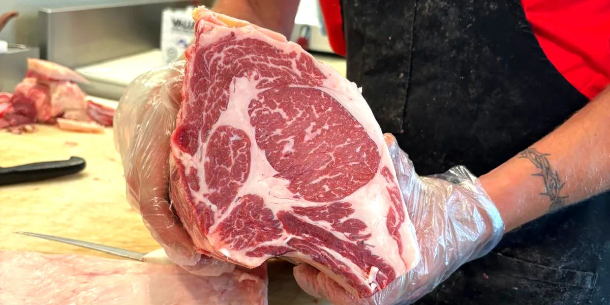 A butcher holding up a freshly cut ribeye