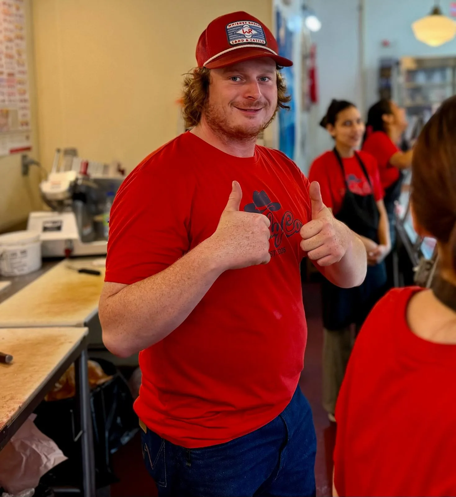 A member of the Herdy Co. team behind the counter, giving two thumbs up